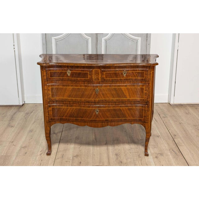 A Tuscan walnut and mahogany commode from circa 1890 with four drawers, banded inlay and bronze hardware. This exquisite...