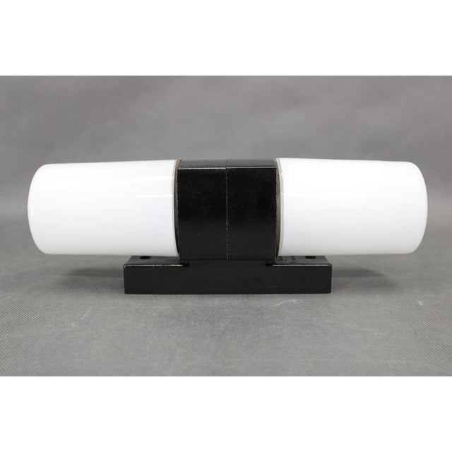 A refined mid-century modern wall light produced in czechoslovakia during the 1960s. The fixture combines a robust...