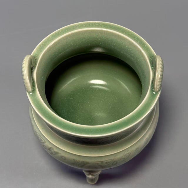 This Chinese Longquan celadon porcelain incense burner is decorated with delicate carved patterns covering the rounded...