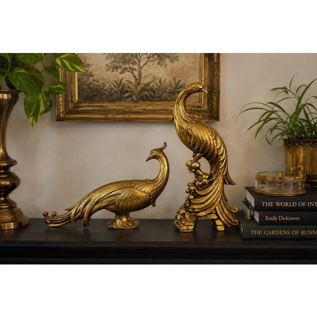Striking vintage Syroco pair of sculptural gold peacocks in classic Hollywood Regency style. This dramatic matched pair...