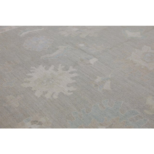 This modern Turkish Oushak rug is a stunning piece of art that has been handwoven using traditional techniques by skilled...