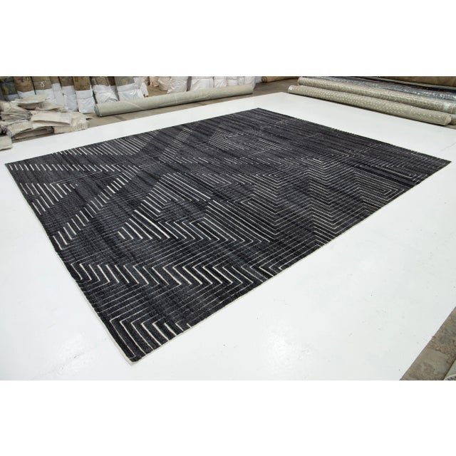 This hand-knotted wool rug in contemporary Moroccan style features a rich charcoal gray field with a striking white...