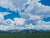 "The Rhythm of the Sky" is an oil on linen landscape painting by Michael Magrin, completed in 2026. Large cumulus clouds...