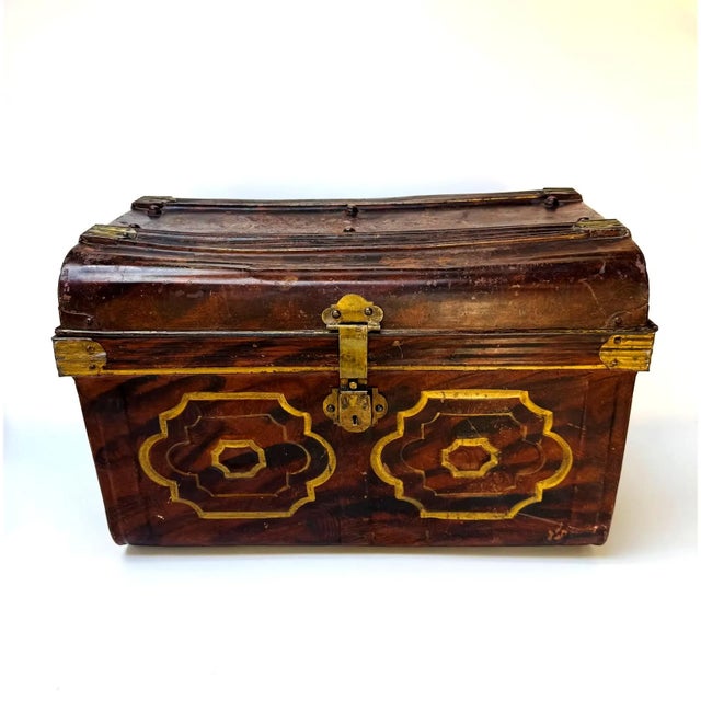Early painted metal trunk with hand-applied decorative panels and brass hardware. Strong visual piece with a deep brown...