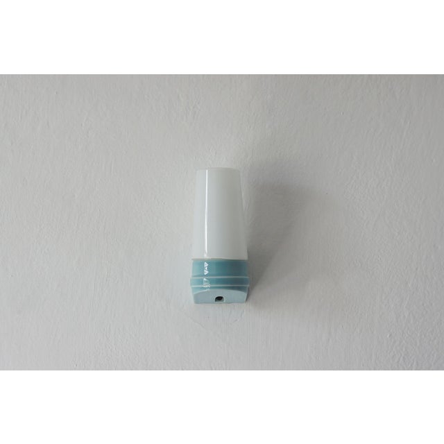 A wall sconce designed by Sigvard Bernadotte for Ifö, representing mid-20th-century Swedish modernism. The form is based...