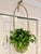Vintage Unique Woven Rattan Hanging Basket. It features a woven round base and a uniquely high, arched handle with a small...