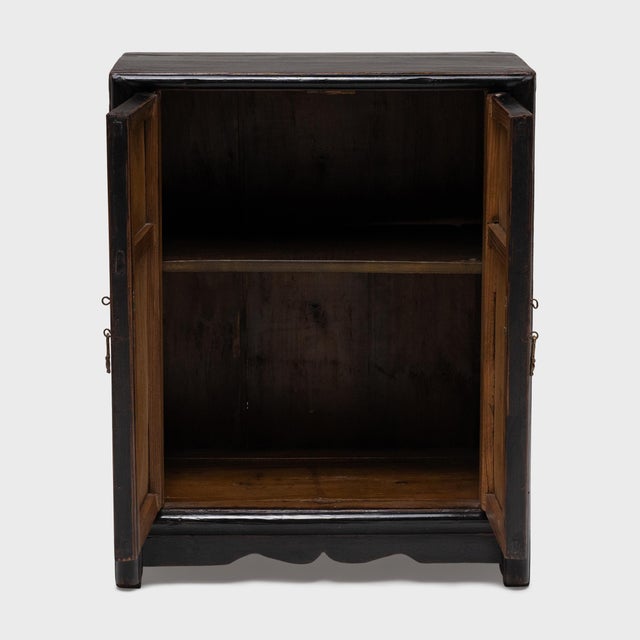 The bold lacquer, paneled front and gilt carvings of this small bedside cabinet exemplify the early 20th-century furniture...