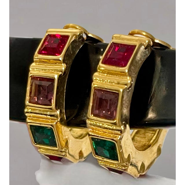 Swarovski gold clip on hoop earrings with faceted crystals in tones of red, green, and purple. Circa 1980s.