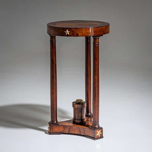 Empire gueridon in walnut, standing on three tall columnar legs with a trefoil base and central plinth. The sides are...