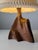 A sculptural table lamp carved from a single piece of solid olive wood. Its asymmetrical, free-form structure is defined...
