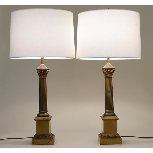 A bold and impressive matched pair of vintage Neoclassical Modern Brass stylized Corinthian Column table lamps designed by...