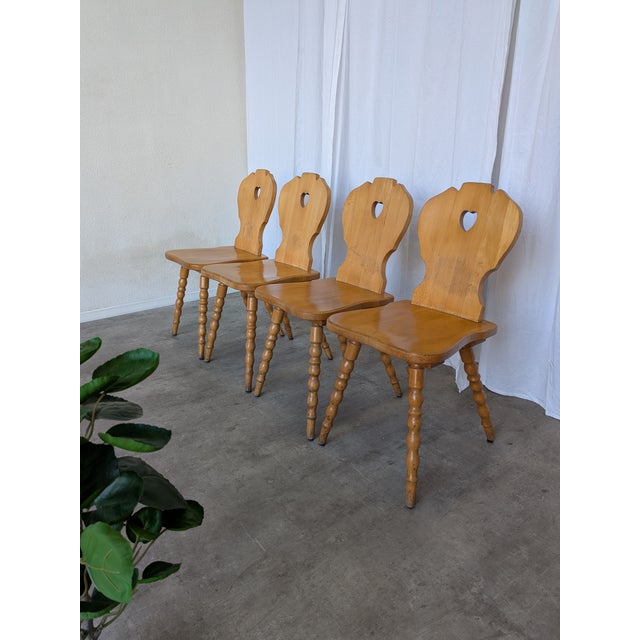 Set of 4 vintage wooden dining chairs in Tyrolean style. The chairs feature solid wooden construction with bobbin-turned...