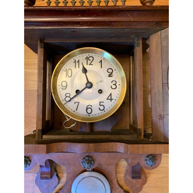 Antique Victorian era wall clock in decorative wood case with pendulum