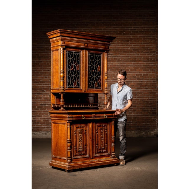 Two-piece Renaissance Revival oak sideboard or china cabinet featuring a projecting molded cornice, turned supports, and...
