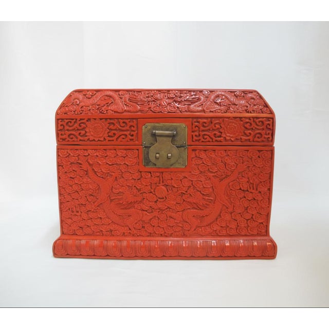 Early 20th century Chinese wood and red Cinnabar lacquer chest with heavily carved dragon motif. The front, side, and lid...