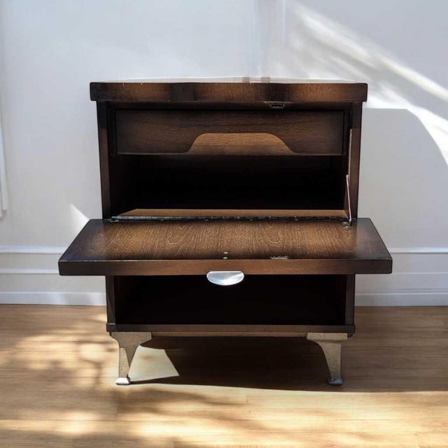 1950s Atomic Walnut Drop-Front Nightstand with Metal Legs. A compact vintage nightstand or side cabinet with a walnut-...