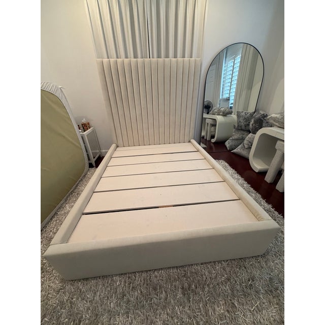 Custom-made queen upholstered bed in luxurious off-white velvet featuring a dramatic vertical channel-tufted headboard....
