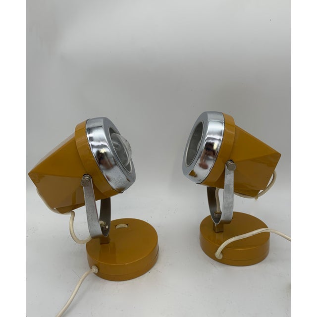 A pair of 1970s-style adjustable space-age table lamps, featuring a conical body in orange lacquered metal and a polished...