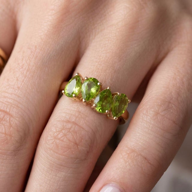 This stunning statement ring showcases a beautiful row of four graduated, pear-cut natural peridot gemstones. Each 6 x 4mm...