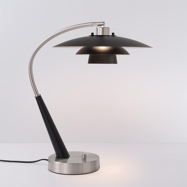 The Boomerang Table Lamp is a Modern table lamp crafted with a sleek silhouette, combining a Black Oak and Satin Nickel...