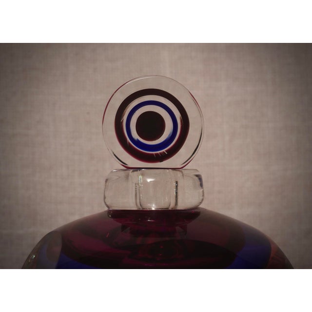 A perfume bottle with internal decorations in various shades of blue, pink, and transparent. A sculpture of the highest...