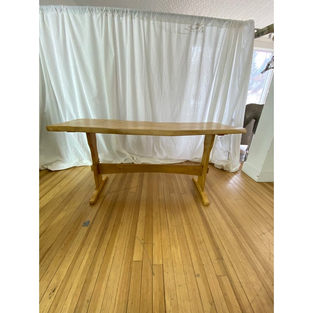 Harnett Wood Designs trestle dining table featuring solid wood construction and a warm natural finish. The table showcases...