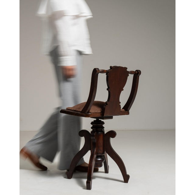 This piece presents as a swivel desk chair, distinguished by dark walnut, turned column base. Dating to 1900s and...