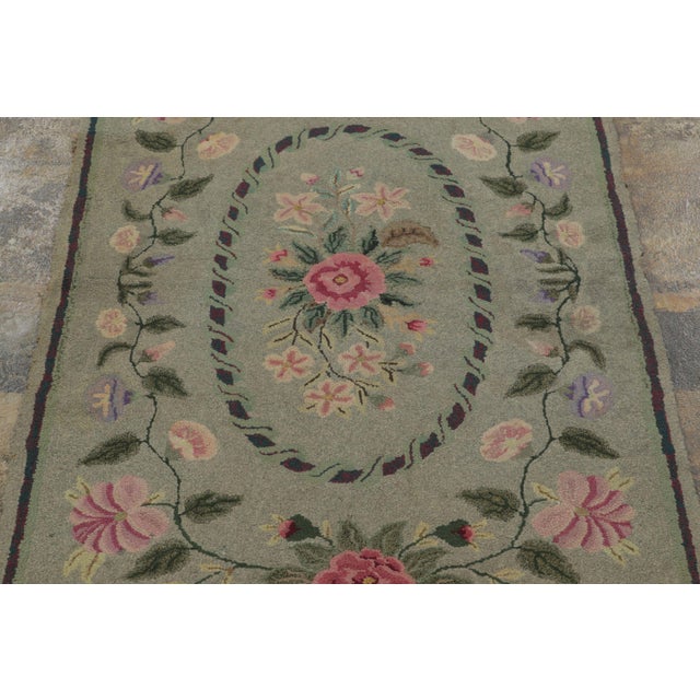 This antique 3x5 hooked rug, circa 1920–1929, features an elegant floral visual juxtaposition set against a soft sage-...