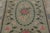 This antique 3x5 hooked rug, circa 1920–1929, features an elegant floral visual juxtaposition set against a soft sage-...