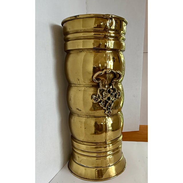vintage or antique brass umbrella stand, also known as a stick or cane stand. It features a decorative handle with an...