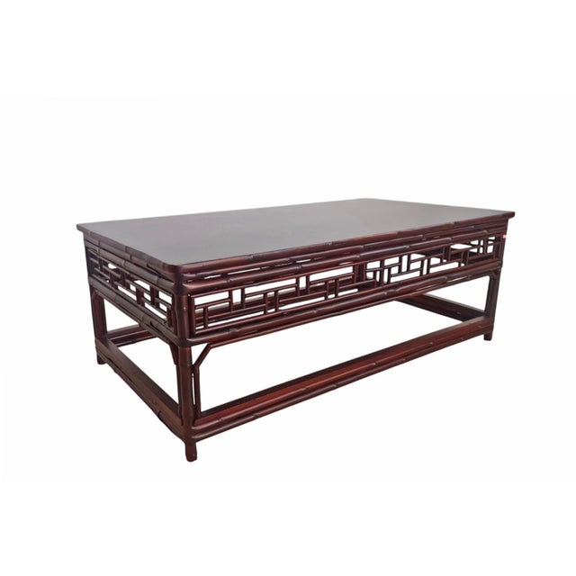 This is a low, rectangular wooden table styled in a classic Chinese traditional aesthetic. It features a deep reddish-...