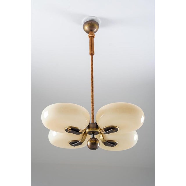 Early ceiling light designed by paavo tynell for taito in the 1930s. The fixture features four cream-coloured glass shades...