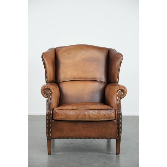 We present this charming sheepskin wing chair in warm colors, finished with decorative nails. This sheepskin wing chair is...