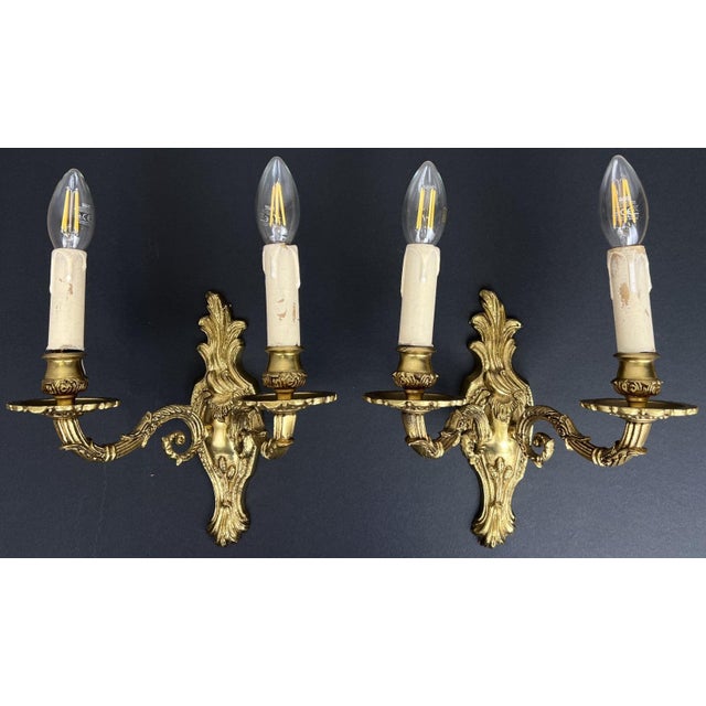 An elegant pair of Vintage French sconces featuring beautifully ornate scrolling arms and decorative detailing throughout....
