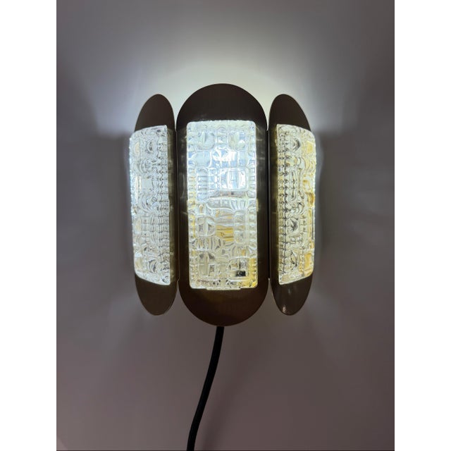 A striking lighting object from Denmark: This golden wall lamp from the Danish manufacturer Vitrika captivates with its...