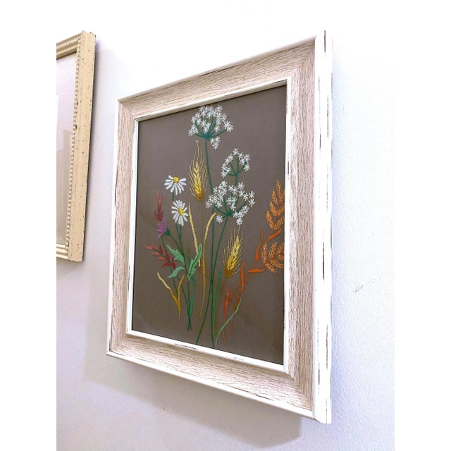 A really pretty bouquet of flowers like babies breath and daisies. Hand stitched on a gray background and framed in a...