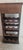 This BUTLER vintage dark wood wine rack cabinet features a top pull-out drawer with a brushed brass-finish front panel and...