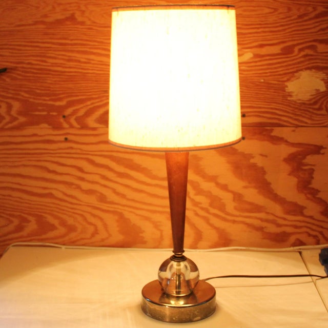 Nicely tapered wood column atop a solid clear glass sphere. Brass finish base. Condition: Good vintage condition, brass...