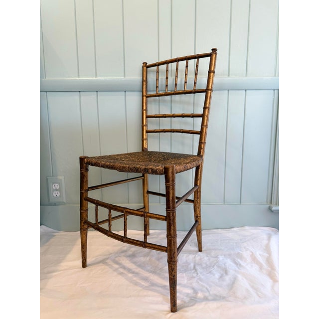 A charming Italian gilt faux bamboo side chair featuring a beautifully woven rush seat and warm, naturally aged patina....