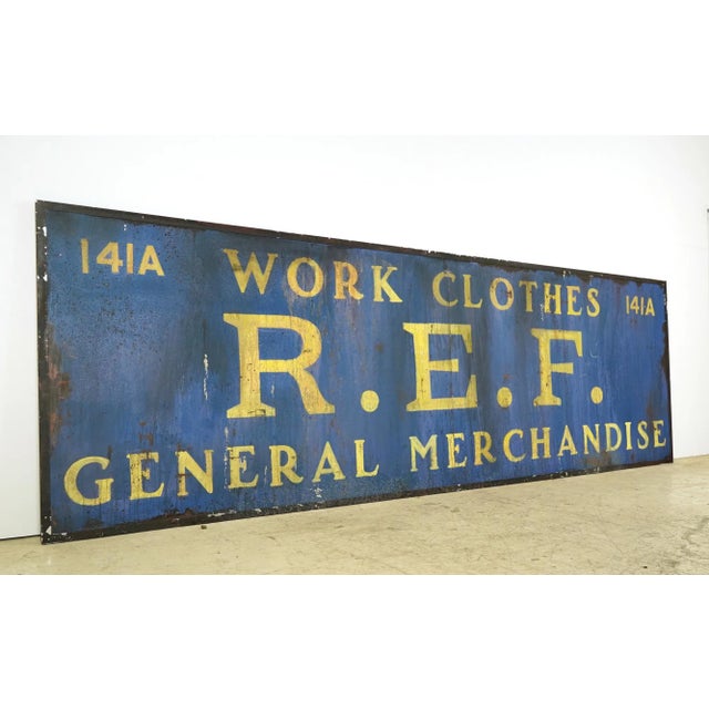 Reclaimed movie set sign made of aluminum in a blue and yellow color. The sign reads "141A, Work Clothes, R.E.F. General...