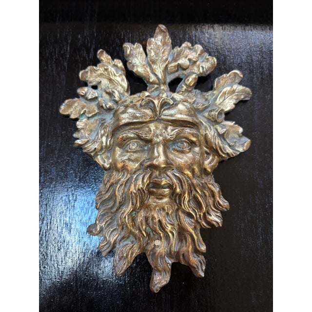 A French or English cast bronze mount depicting a Roman God, possibly Bacchus, surrounded by oak leaves and acorns,...