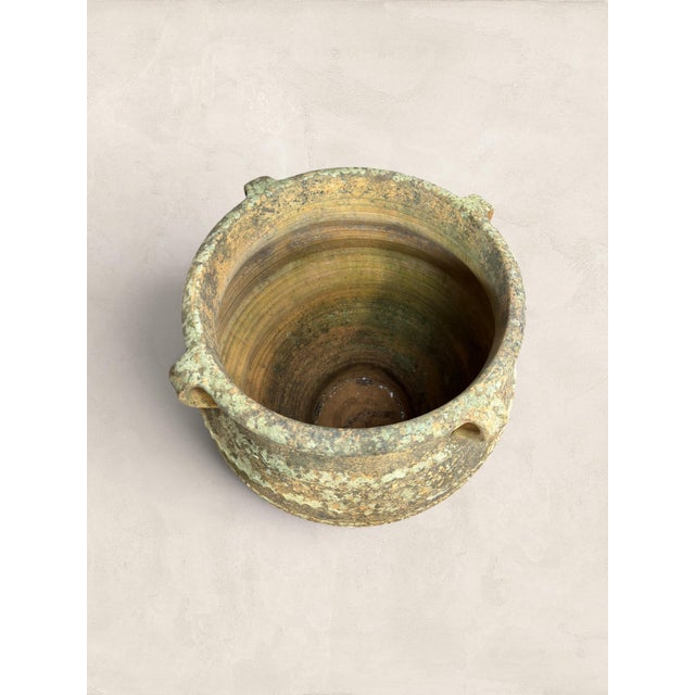 A striking late 19th-century Greek terracotta olive jar, dating to circa 1890, featuring beautifully preserved hand-...