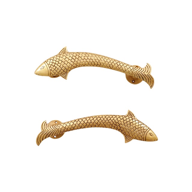 A pair of brass fish shaped door handles or cabinet pulls, made of brass and cast with line details to show eyes, scales...