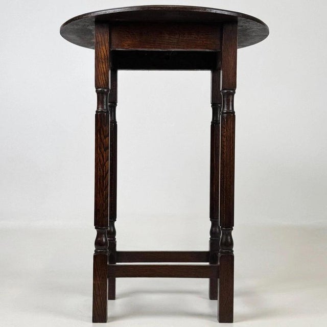 A charming early 20th-century English side table, finely crafted from oak and distinguished by its elegant oval top,...