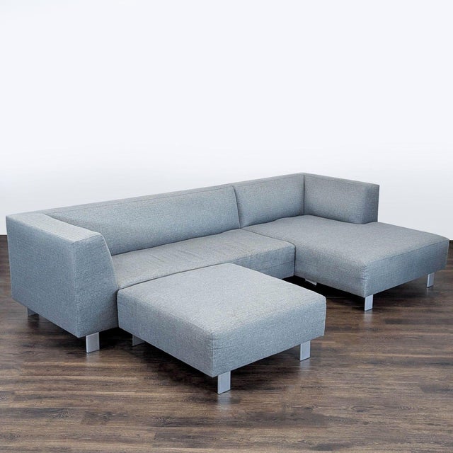 This Room and Board sectional sofa features a clean, modern design in a versatile gray fabric. It includes an ottoman for...