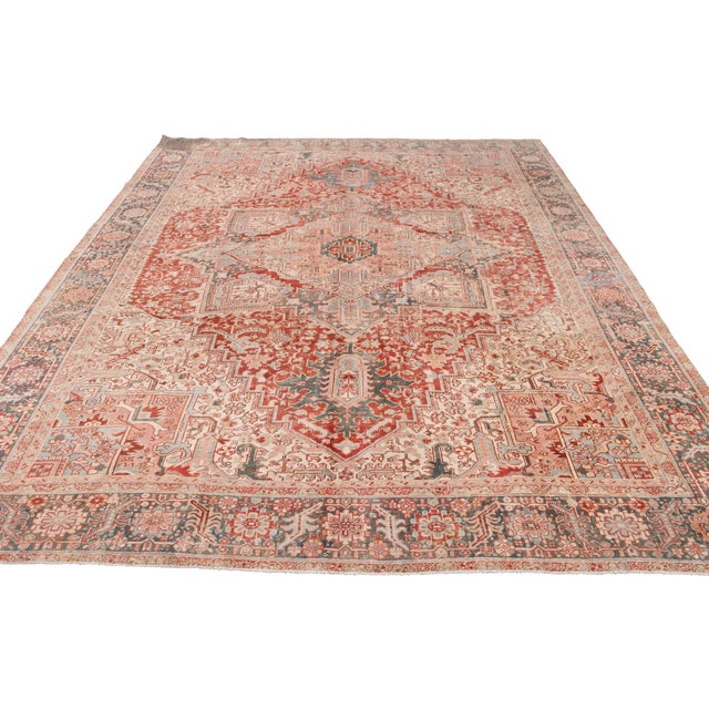 The captivating beauty of this antique hand-knotted Persian Heriz wool rug, with vibrant colors against a rich red...
