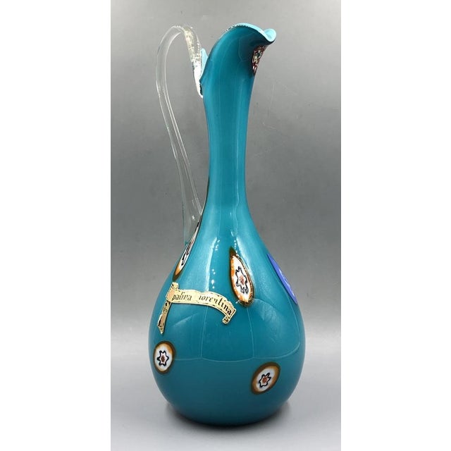 This elegant, light blue Murano glass jug, made using the traditional Opalina Fiorentina technique, impresses with its...