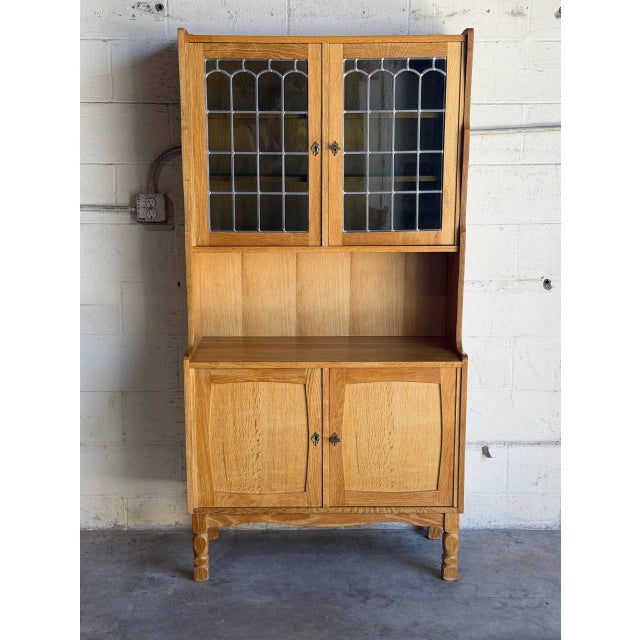 Leaded glass upper doors reveal interior display shelves set above a wide open counter space and lower cabinet storage....