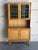 Leaded glass upper doors reveal interior display shelves set above a wide open counter space and lower cabinet storage....