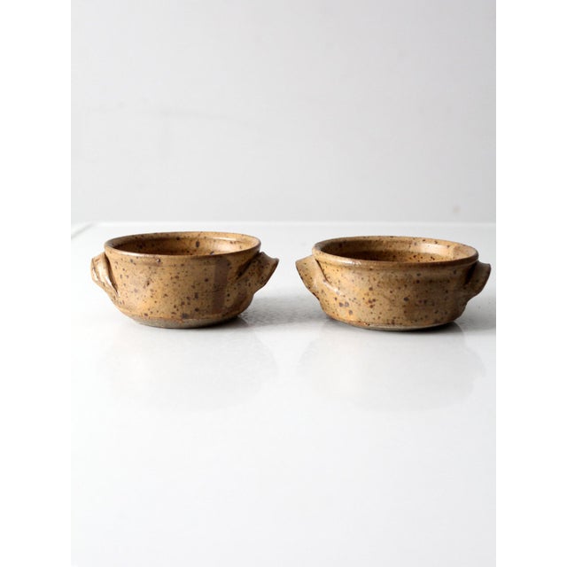 This matched pair of vintage handmade studio pottery bowls celebrates form, texture, and natural warmth. Finished in a...